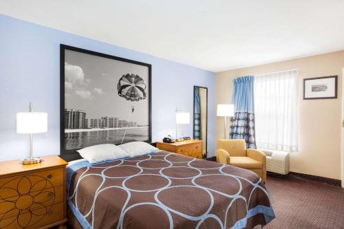 a hotel room with a bed and a chair at Super 8 by Wyndham Foley in Foley