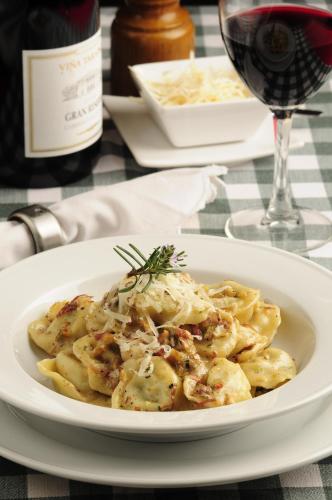 a plate of pasta on a table with a glass of wine at L'Emiliano Cabañas-Ristorante in Capitán Pastene