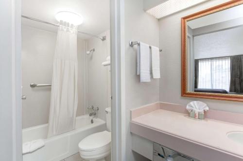 La salle de bains est pourvue de toilettes, d'un lavabo et d'un miroir. dans l'établissement Super 8 by Wyndham Longview/North, à Longview