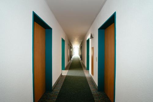 a hallway with doors and a long hallway with green carpet at Hotel Residenz in Schnelldorf