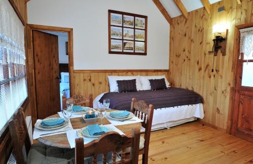 a bedroom with a bed and a table and chairs at L'Emiliano Cabañas-Ristorante in Capitán Pastene