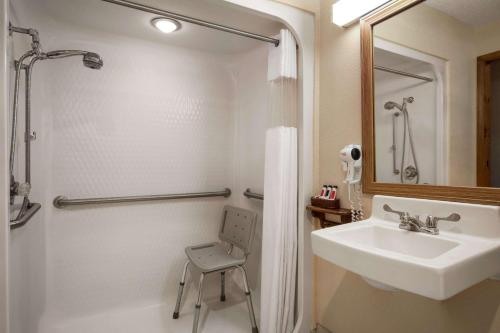 a white bathroom with a sink and a shower at Baymont by Wyndham Logan in Logan