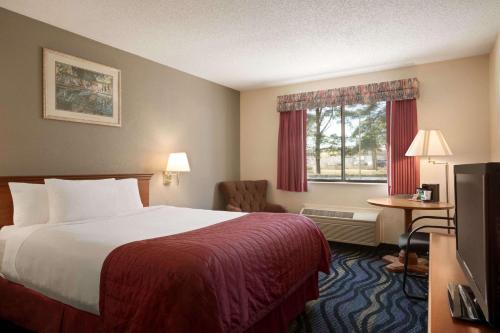 a hotel room with a bed and a window at Baymont by Wyndham Logan in Logan
