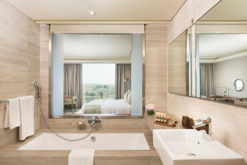 a bathroom with a tub and a large mirror at Grand Millennium Muscat in Muscat