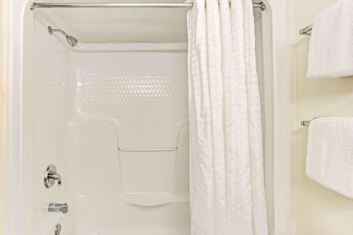 a shower with a white shower curtain in a bathroom at Super 8 by Wyndham Gurnee in Gurnee