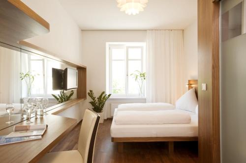a bedroom with a bed and a desk and a table at Hotel Constantia in Konstanz