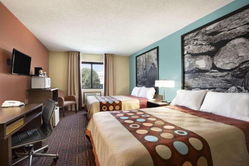a hotel room with two beds and a desk at Super 8 by Wyndham Carbondale in Carbondale