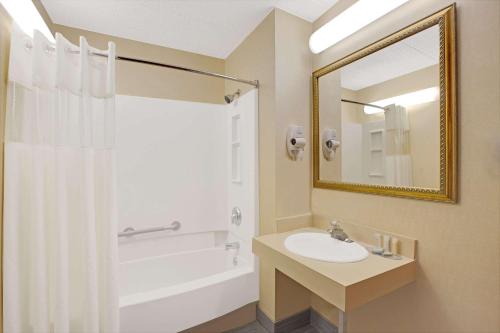 een badkamer met een wastafel, een bad en een spiegel bij Travelodge by Wyndham Parsippany in Parsippany