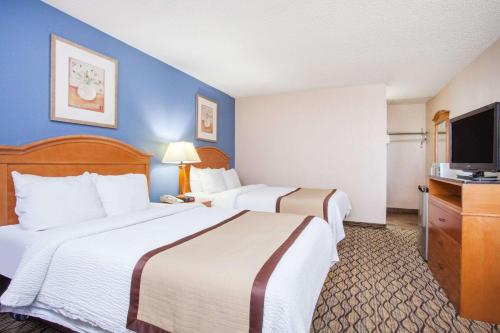 a hotel room with two beds and a flat screen tv at Baymont by Wyndham Madison Heights Detroit Area in Madison Heights