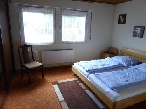 um quarto com uma cama, uma cadeira e 2 janelas em Ferienwohnung am Liebesgrund em Lüneburg
