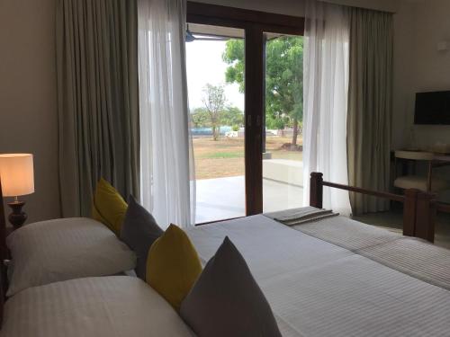 a bedroom with two beds and a large window at The Palmyrah House in Mannar
