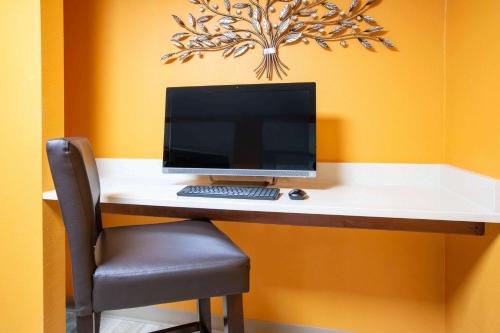 a computer monitor sitting on a desk with a chair at Baymont by Wyndham Plano in Plano