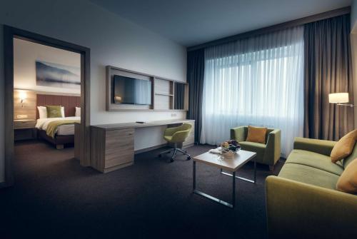a hotel room with a couch and a desk with a television at Wyndham Garden Astana in Astana