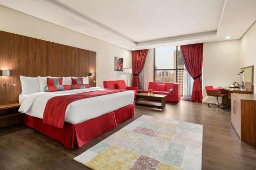 a hotel room with a large bed and a desk at Ramada Encore by Wyndham Kuwait Downtown in Kuwait