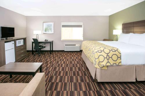 a hotel room with a large bed and a desk at Baymont by Wyndham Plano in Plano