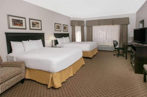a hotel room with two beds and a television at Baymont by Wyndham Roswell in Roswell