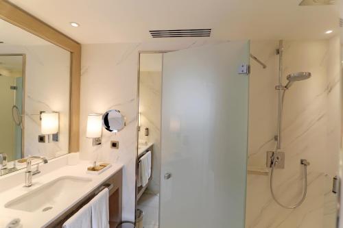 a white bathroom with a shower and a sink at Hôtel Alchimy in Albi
