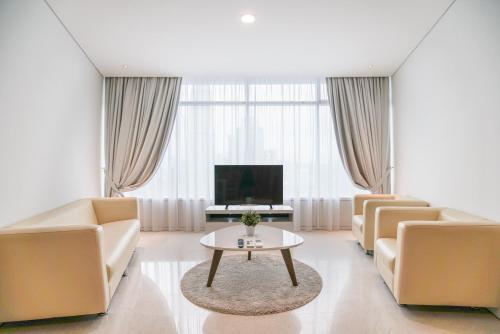a living room with couches and a tv and a table at The Penthouse KLCC in Kuala Lumpur