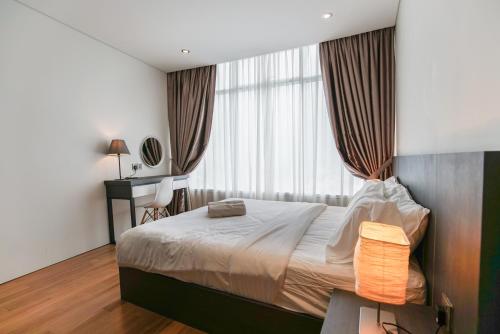 a bedroom with a bed and a desk and a window at The Penthouse KLCC in Kuala Lumpur