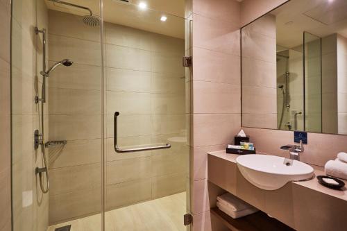 a bathroom with a glass shower and a sink at D'Resort @ Downtown East in Singapore