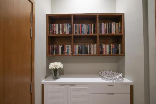 a book shelf with a vase of flowers on a desk at The Penthouse KLCC in Kuala Lumpur
