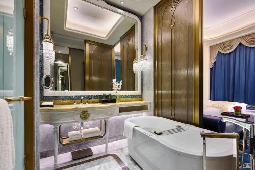 La salle de bains est pourvue d'une baignoire et d'un grand miroir. dans l'établissement Wanda Vista Qingdao Movie Metropolis, à Huangdao