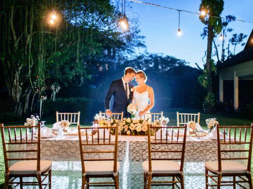 a bride and groom kissing at a wedding table at Novotel Bali Nusa Dua in Nusa Dua