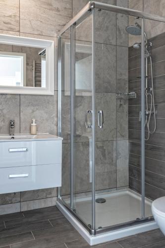 a glass shower in a bathroom with a sink at Bornholm Panorama Apartments in Svaneke
