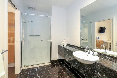 a bathroom with a glass shower and a sink at Belmercer Motel in Geelong