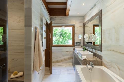 ein Badezimmer mit einer Badewanne, einem Waschbecken und einem Spiegel in der Unterkunft Elounda Mare Relais & Châteaux Hotel in Elounda