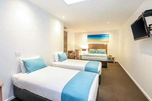 a hotel room with two beds and a tv at Belmercer Motel in Geelong