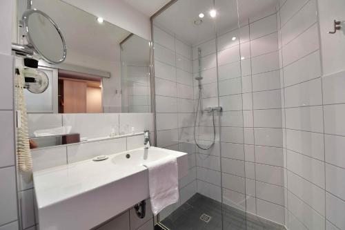a white bathroom with a sink and a mirror at Hotel Aspethera in Paderborn