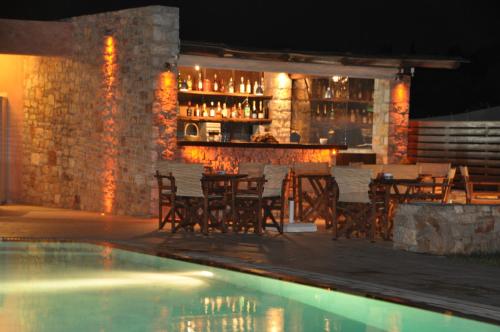 a restaurant with a bar with chairs and a pool at Petradi in Livadi