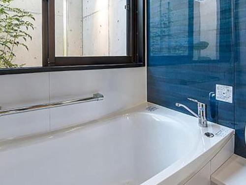 a bathroom with a bath tub with a window and a sink at ホテルコンドミニアム土花土花 in Onna
