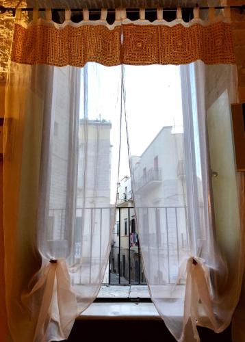 a window with white curtains and a view of a city at L'Orecchietta 2.0 in Ruvo di Puglia