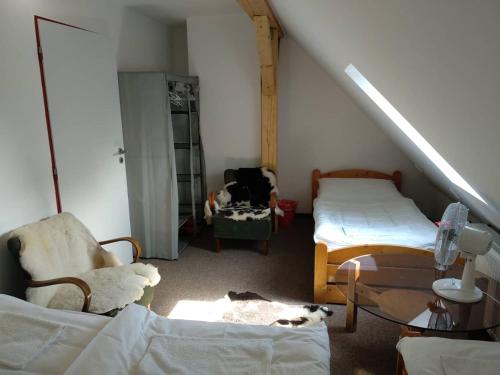 a attic room with two beds and a chair at Rodinné vinařství Mikulenkovi in Žernoseky