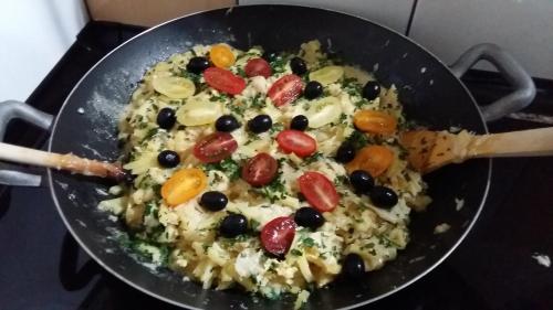 a pan full of rice with olives and tomatoes at Casa o Futuro in Alcobaça