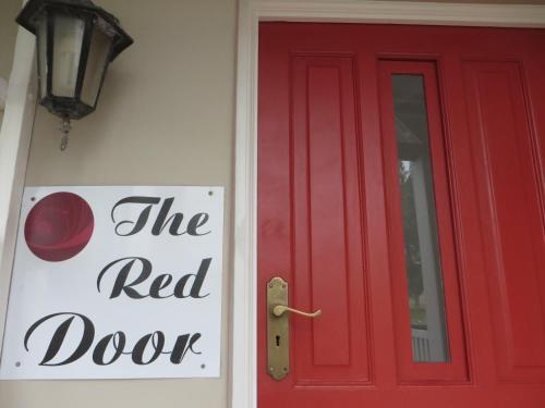 a red door with a red door sign next to it at Rose and Ale Self Catering Units in Gonubie