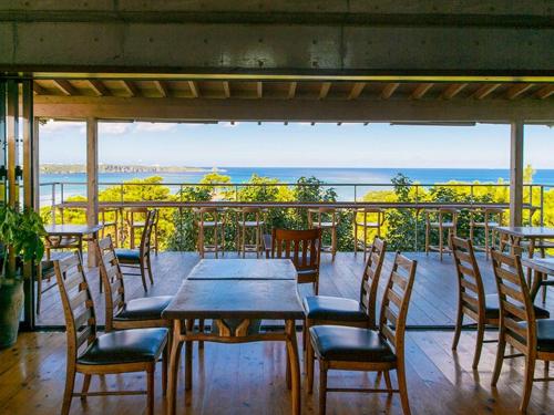 a table and chairs on a balcony with a view of the ocean at ホテルコンドミニアム土花土花 in Onna