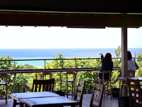 two women taking a picture of the ocean from a balcony at ホテルコンドミニアム土花土花 in Onna