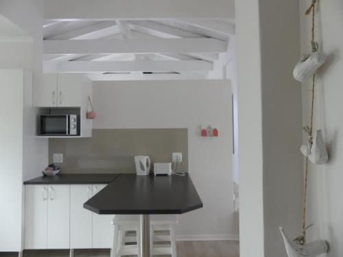a kitchen with white cabinets and a black counter top at Rose and Ale Self Catering Units in Gonubie