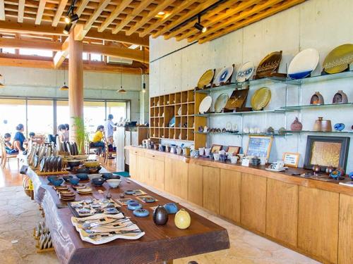 a room with a long table with plates and bowls at ホテルコンドミニアム土花土花 in Onna