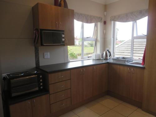 a kitchen with wooden cabinets and a microwave and a window at Rose and Ale Self Catering Units in Gonubie