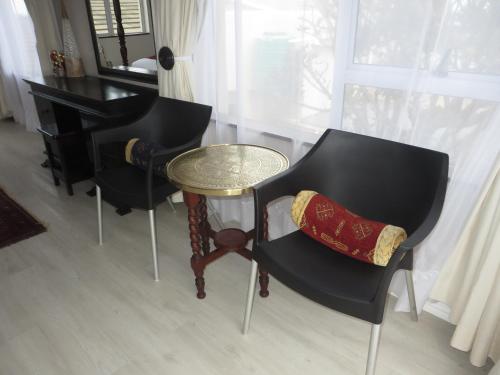 a room with two chairs and a table and a piano at Rose and Ale Self Catering Units in Gonubie