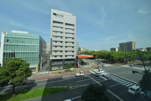 高松多美迎高松中央公园前酒店的城市中一座高大的白色建筑,设有停车场