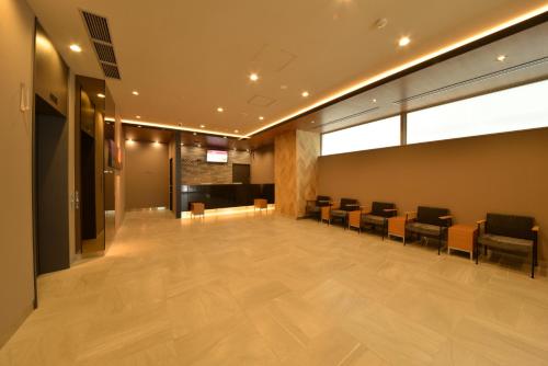 an empty waiting room with chairs and a table at Dormy Inn Takamatsu Chuo Koenmae Natural Hot Spring in Takamatsu