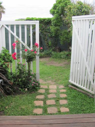 a garden with a white gate and some flowers at Rose and Ale Self Catering Units in Gonubie