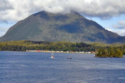a boat in a large body of water with a mountain at Himwitsa Lodge in Tofino