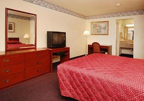 ein Hotelzimmer mit einem roten Bett und einem Spiegel in der Unterkunft Driftwood in Santa Clara