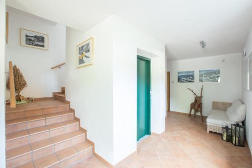 a white hallway with stairs and a green door at Appartementhaus Elmo Viehhauser KG in Kleinarl